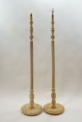 A pair of standard lamps, each with fluted columns and round bases painted cream,