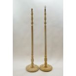 A pair of standard lamps, each with fluted columns and round bases painted cream,