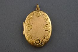 A hallmarked 9 carat gold oval locket with floral engraved design and satin/polished finish.