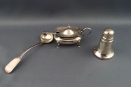 A silver mustard pot, with shaped flared feet and blue glass liner, and an associated spoon,