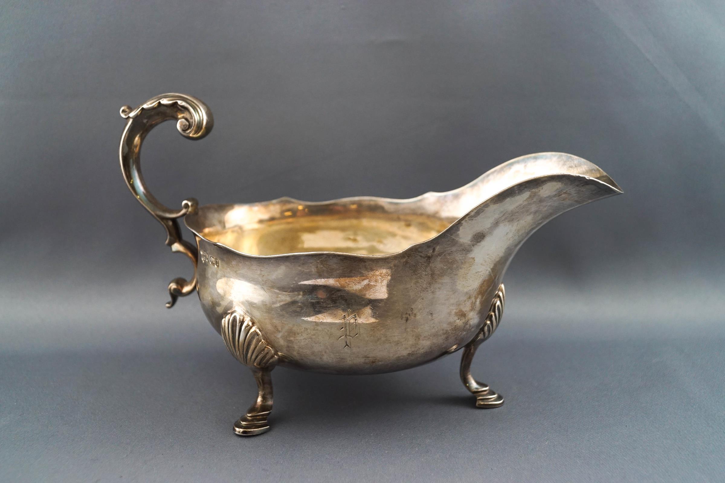 A late Victorian silver sauce boat, with double C scroll handle on three cast hoof feet,