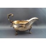 A late Victorian silver sauce boat, with double C scroll handle on three cast hoof feet,