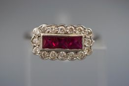 A white metal ring set with three square rubies measuring 3.00mm.