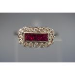 A white metal ring set with three square rubies measuring 3.00mm.