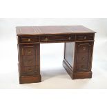 A 20th century mahogany kneehole desk with leather inset top over an arrangement of seven drawers,