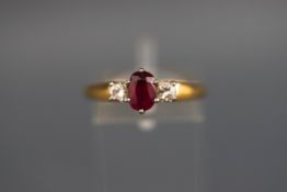 A hallmarked 18ct gold three stone ring set with an oval ruby measuring 6.5mm x 4.5m.