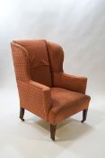 A late 19th century wingback armchair on square tapering legs with brass casters,