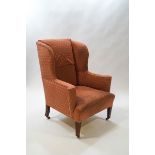 A late 19th century wingback armchair on square tapering legs with brass casters,