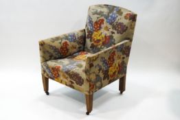 A late Victorian armchair with floral patterned upholstery on oak tapering legs,