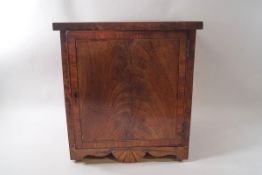 A 19th century mahogany hanging cabinet with cross banded drawer and shaped apron