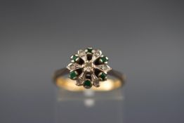 A hallmarked 18ct gold flower cluster ring set with six round emeralds measuring 1.80mm diameter.