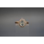 A hallmarked 9ct gold cluster ring set with a central oval aquamarine, surrounded by diamonds.