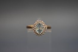A hallmarked 9ct gold cluster ring set with a central oval aquamarine, surrounded by diamonds.