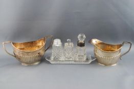 A silver half reeded cream jug and matched two handled sugar bowl, Chester 1921 and Sheffield 1909,