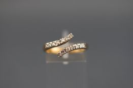A hallmarked 9ct gold crossover ring set with fourteen single cut diamonds measuring approximately
