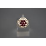 A white metal cluster ring set with seven round rubies measuring 2.