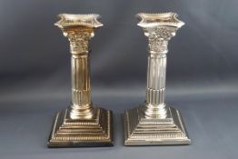 A pair of silver Corinthian column candlesticks, each with detachable sconces on stepped bases,