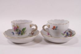 A pair of Meissen porcelain coffee cups and saucers painted in enamels with flower sprays,