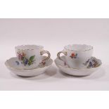 A pair of Meissen porcelain coffee cups and saucers painted in enamels with flower sprays,