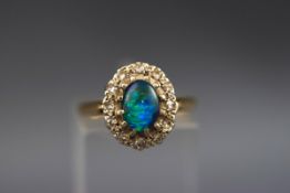 A hallmarked 18ct gold cluster ring set with an oval opal triplet and surrounded by twelve single