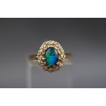 A hallmarked 18ct gold cluster ring set with an oval opal triplet and surrounded by twelve single