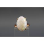 A yellow metal single stone ring set with an oval cabochon opal measuring approximately 18.8mm x 12.