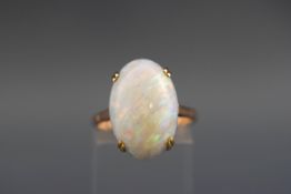 A yellow metal single stone ring set with an oval cabochon opal measuring approximately 18.8mm x 12.