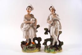 A pair of 19th century Staffordshire pottery figures of a lady with a lamb and her male companion