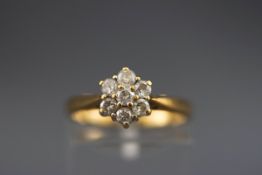 A hallmarked 18ct gold flower cluster ring set with seven round brilliant cut diamonds.