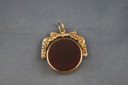 A hallmarked 9 carat gold swivel fob pendant set with carnelian and agate. Scroll design.