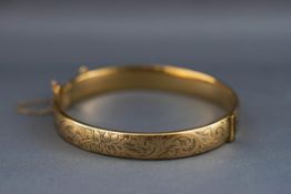 A yellow metal hollow bangle with filigree design.