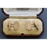 A boxed pair of hallmarked 9 carat gold oval cufflinks with engine turned design.