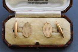 A boxed pair of hallmarked 9 carat gold oval cufflinks with engine turned design.