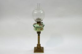 A Victorian brass Corinthian column oil lamp with painted glass reservoir and etched globe shade,