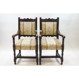 A pair of Victorian carved oak elbow chairs on turned and block legs,