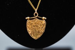 A hallmarked 9ct gold locket in the design of a shield having filigree scroll engraved design.