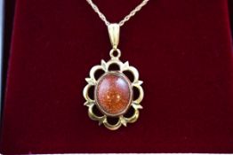 A hallmarked 9 carat gold pendant set with an oval cabochon cut sunstone measuring approximately 10.
