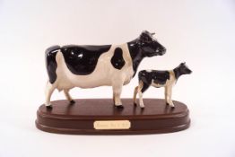 A Beswick model of a Friesian cow and her calf, printed factory marks, on wooden plinth, 24cm long,