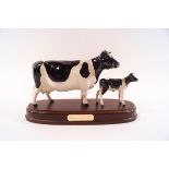 A Beswick model of a Friesian cow and her calf, printed factory marks, on wooden plinth, 24cm long,