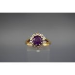 A hallmarked 18ct gold cluster ring set with a round amethyst measuring 7.