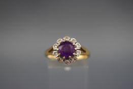 A hallmarked 18ct gold cluster ring set with a round amethyst measuring 7.
