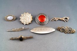A selection of eight silver brooches, to include three gem set,