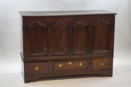 An 18th century oak mule chest with two cupboard doors bearing carved ogee shaped arches above