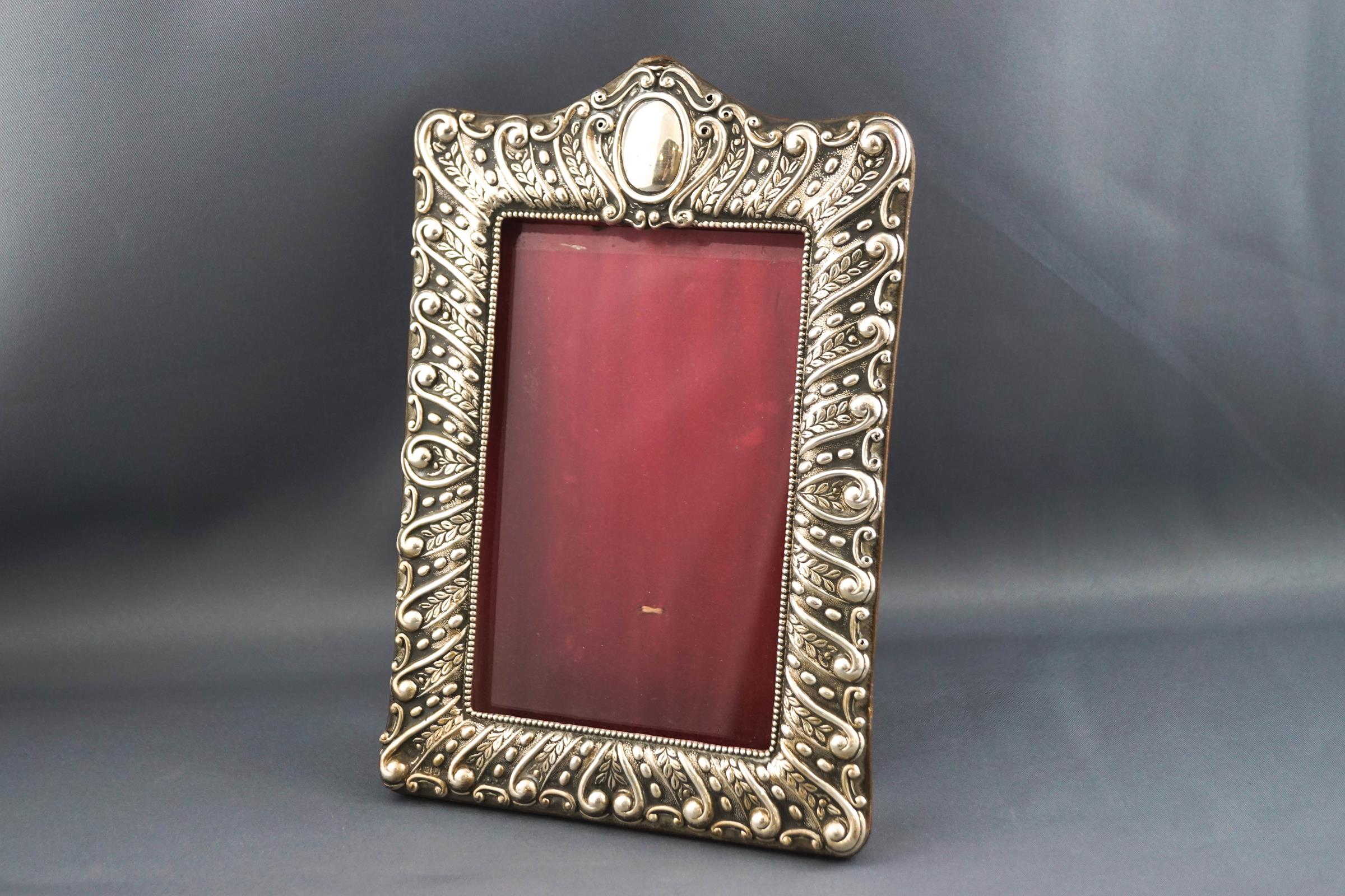 A Victorian silver embossed photograph frame, with red leather back and easel stand,