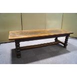 A large oak refectory table with baluster turned legs linked by an 'H' stretcher,