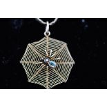 A yellow metal spider web pendant having a central spider set with aquamarine and seed pearl.