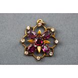An Edwardian pendant set with five rhodolite garnets and surrounded by eight colourless synthetic