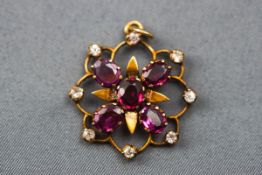 An Edwardian pendant set with five rhodolite garnets and surrounded by eight colourless synthetic