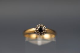 A yellow gold cluster ring set with an oval sapphire and ten single cut diamonds.