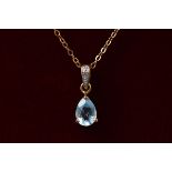 A yellow gold blue topaz and diamond pendant on a fine 9ct gold trace link chain. 1.